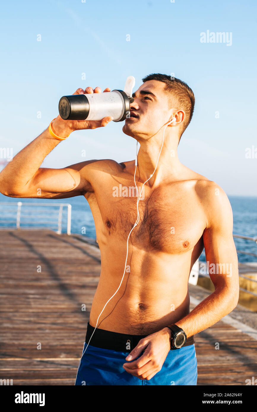 Montare l'uomo utilizzando il suo telefono mentre acqua potabile dopo un duro allenamento. Foto Stock