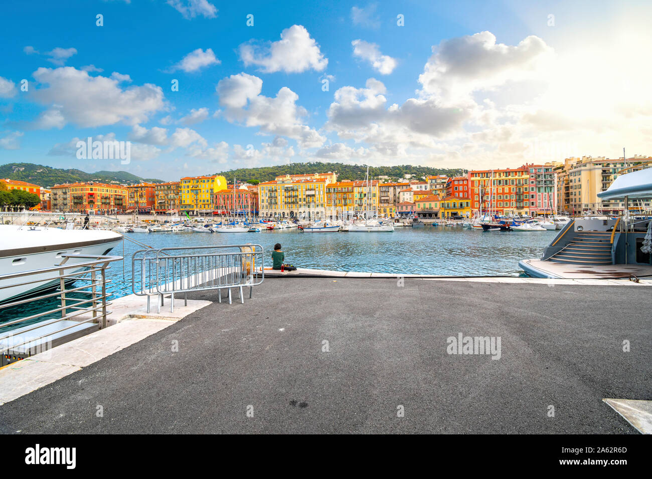 Una donna che mangia il suo pranzo da solo lungo il dock presso il coloratissimo porto vecchio della città mediterranea di Nizza, Francia, lungo la Riviera Francese. Foto Stock