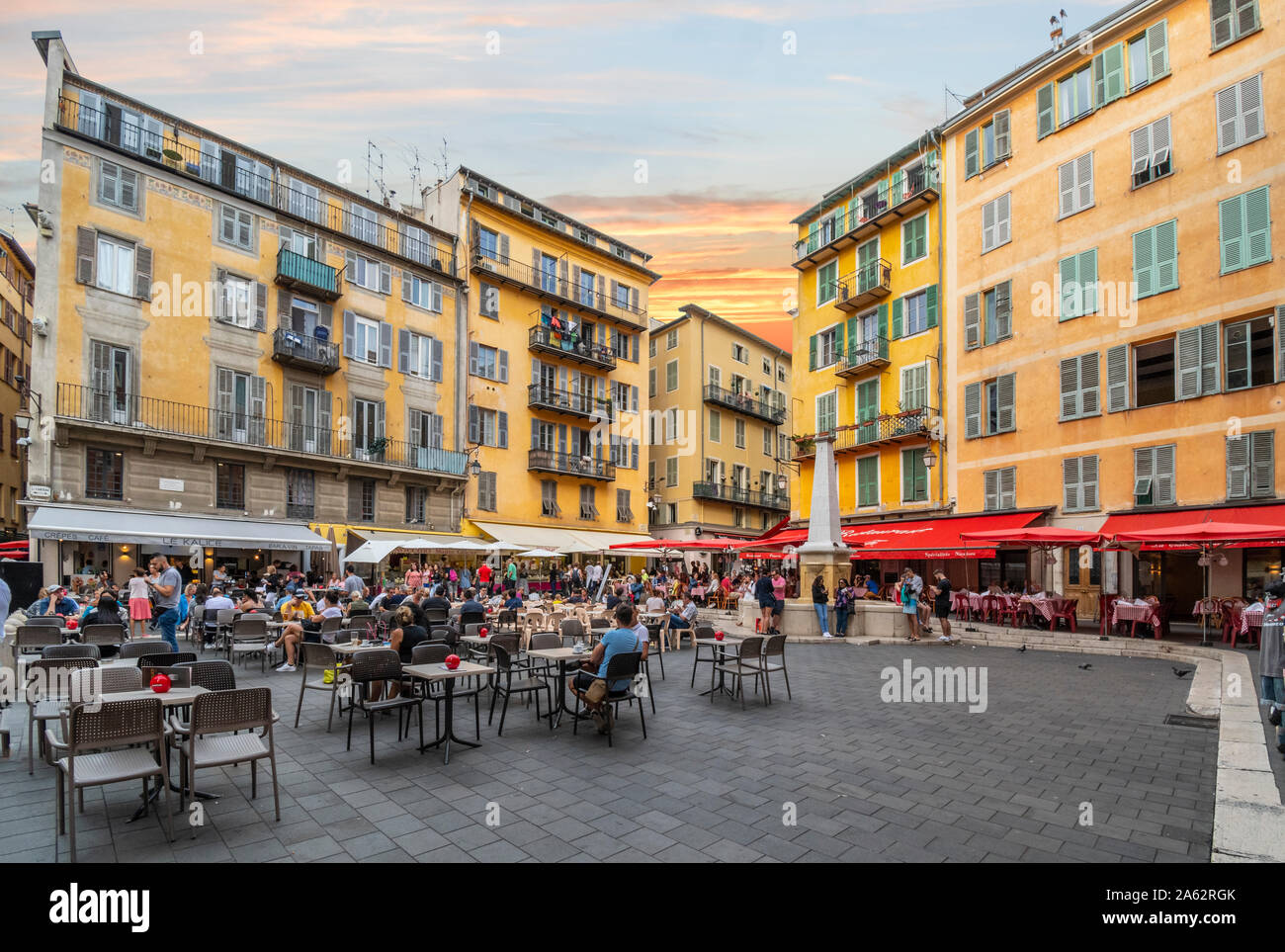 I turisti e i locali godono di un inizio serata presso il cafè, fontana di acqua e negozi al posto di Rossetti, una delle piazze principali di Vieux Nice Francia Foto Stock
