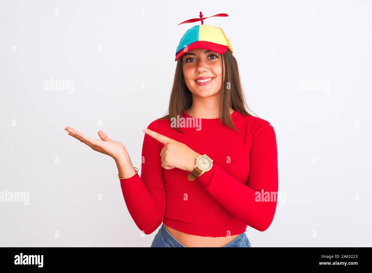 Giovane bella ragazza indossando fanny cappello con elica in piedi isolato  su sfondo bianco stupiti e sorridente alla fotocamera durante la  presentazione con h Foto stock - Alamy