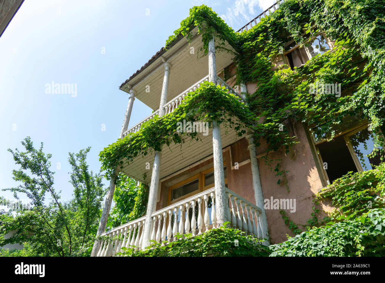 Stile di fotografia di stock di vintage balcone in legno coperto con foglie d'uva. Retrò casa a due piani in stile mediterraneo utile per foto manipu Foto Stock