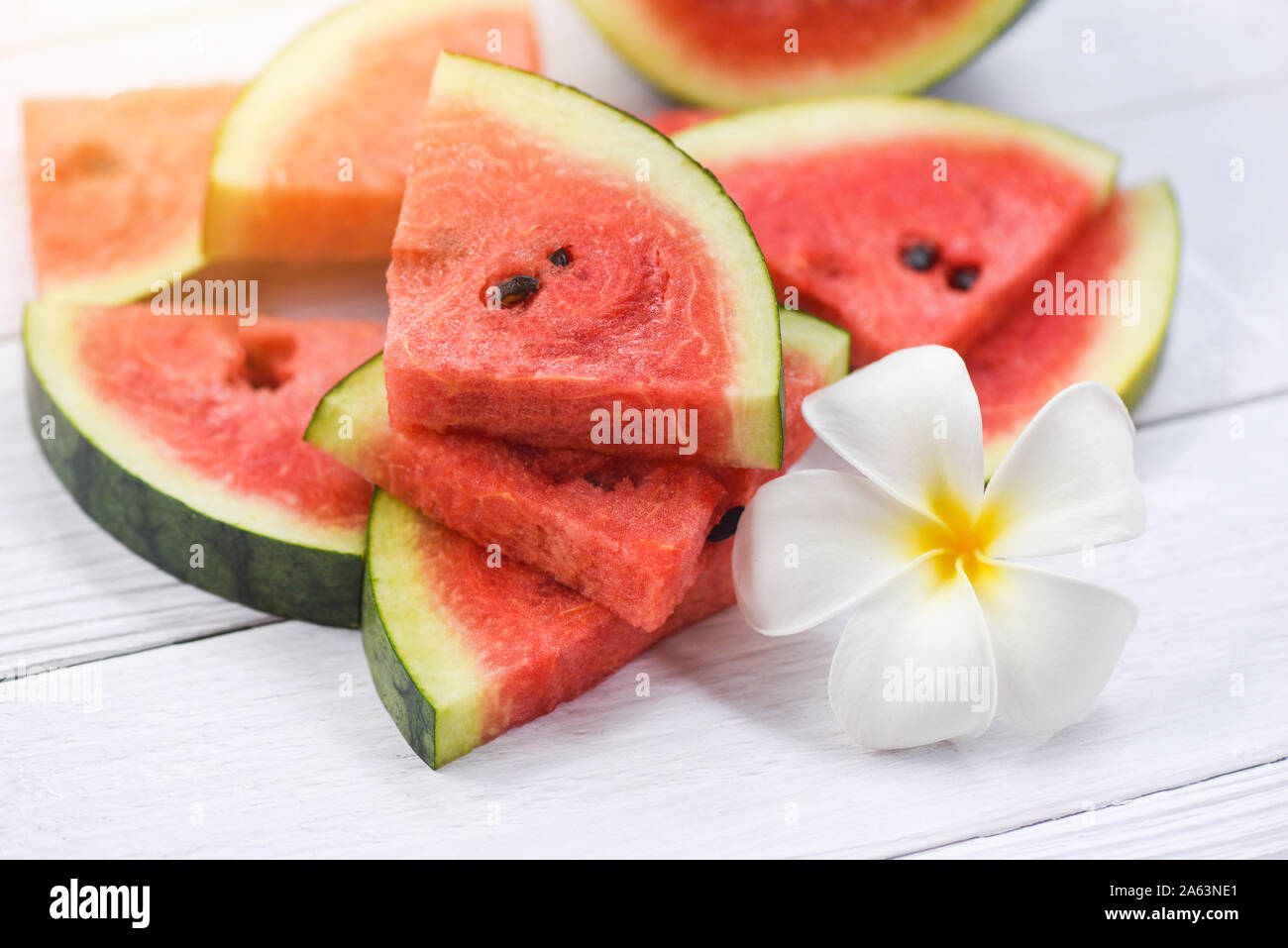 Anguria fresca su sfondo di legno / pila di rosso le fette di cocomero e fiore bianco Foto Stock