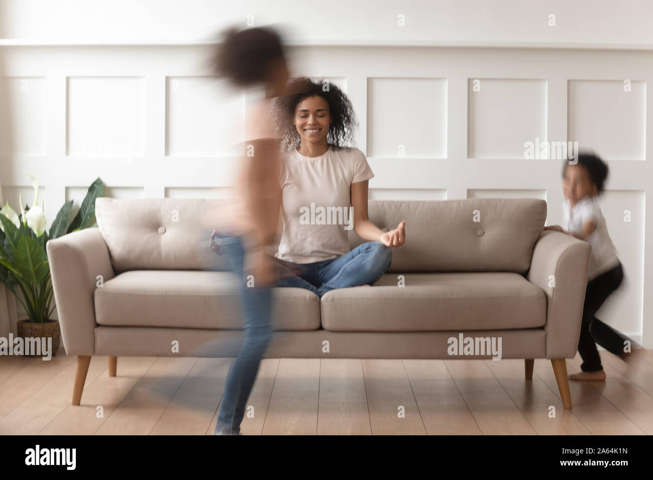 Felice mom nero la pratica dello yoga con i bambini attivi intorno Foto Stock