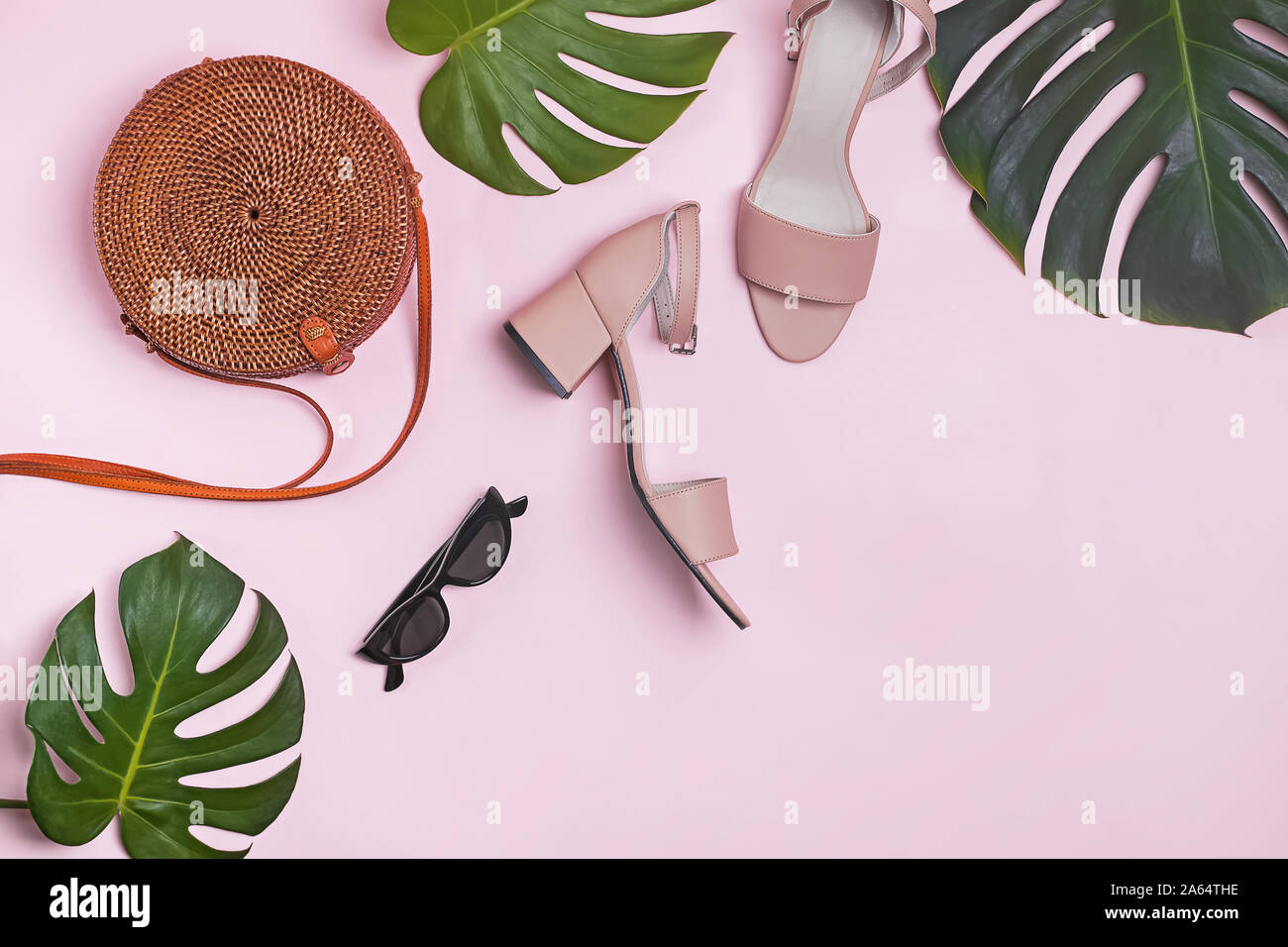 Elegante estate femminile accessori e foglie di monstera sul rosa pastello, sfondo Foto Stock