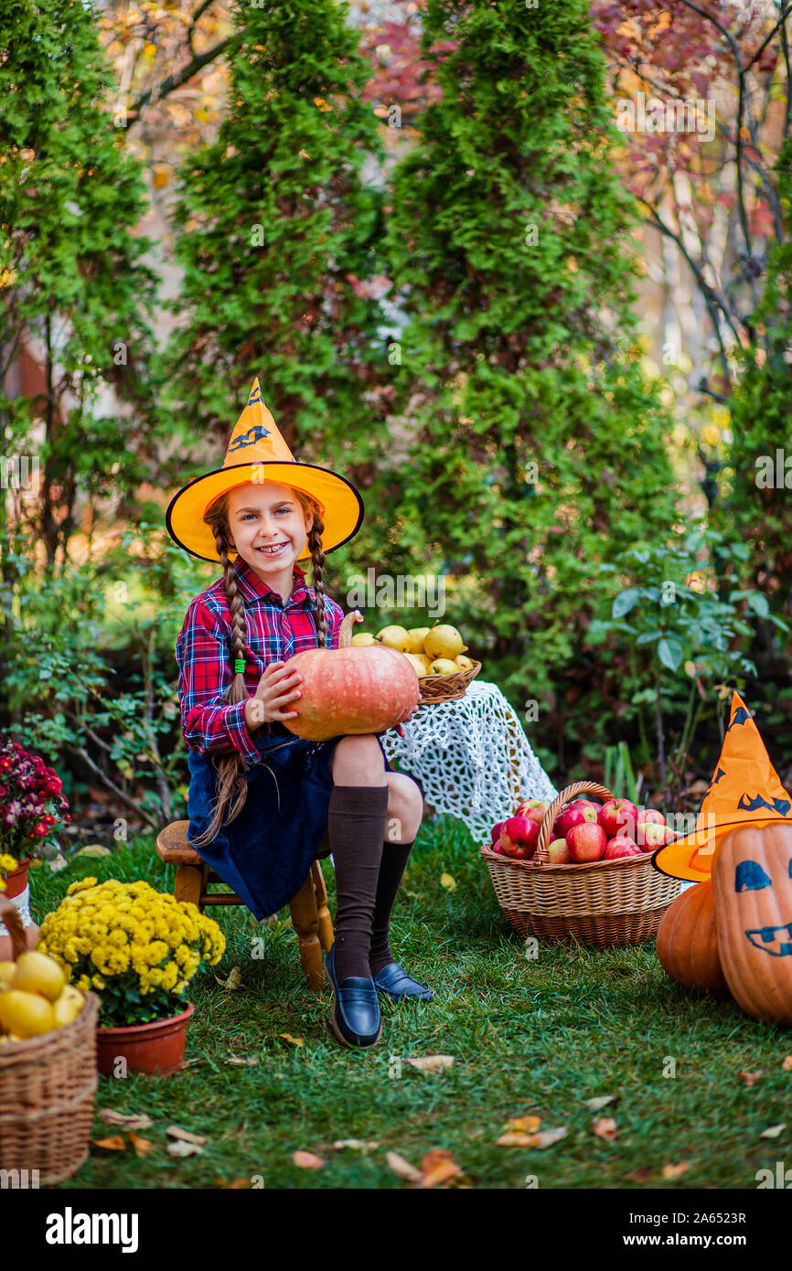 Carino bambina abbraccia una zucca in giardino d'autunno. Celebrando raccolto autunnale. Foto Stock