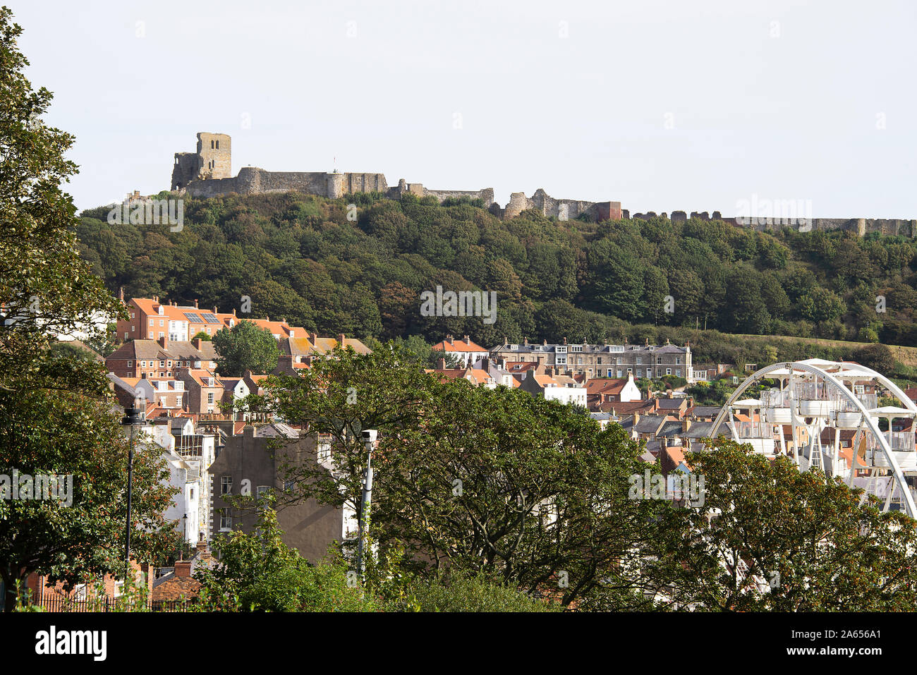 Vista del Castello di Scarborough sulla scogliera del Castello e parte della città di Seaside con Woodland e Big Wheel North Yorkshire Inghilterra Regno Unito Foto Stock