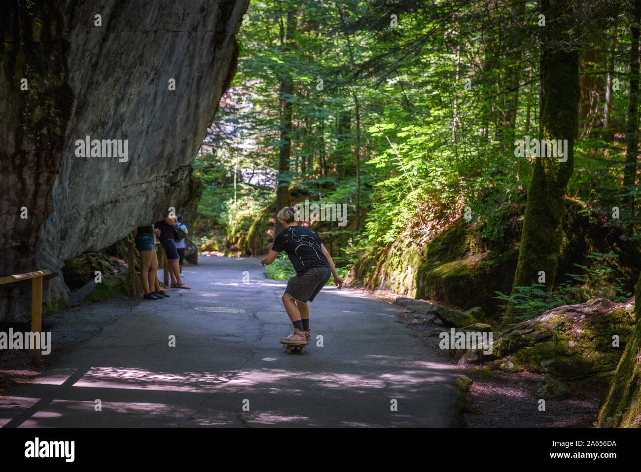 Pattinatore cavalcare uno skateboard su una strada verso il lago Blausee in Svizzera Foto Stock