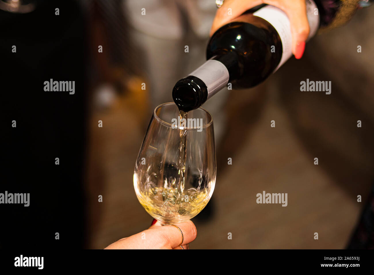 Persona che serve un bicchiere di vino nel bicchiere di vetro in una cantina scuro Foto Stock
