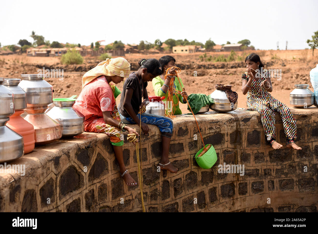 Le donne di raccogliere l'acqua dal pozzetto a mal village, Shahapur Thane Maharashtra, India, Asia Foto Stock