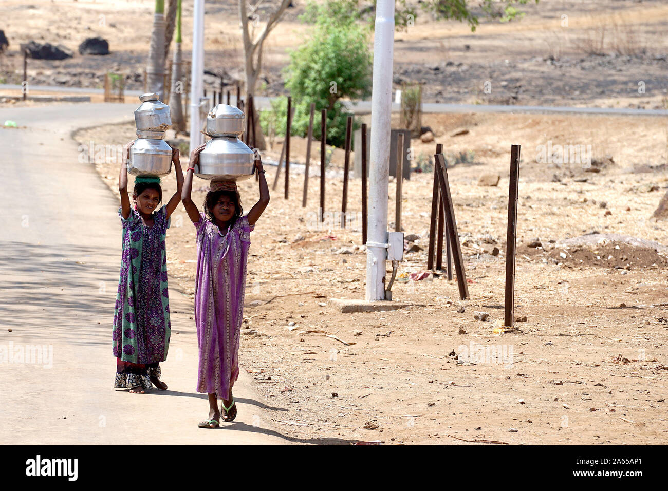Le giovani ragazze che trasportano pentole di acqua dal bene al mal village, Thane, Maharashtra, India, Asia Foto Stock