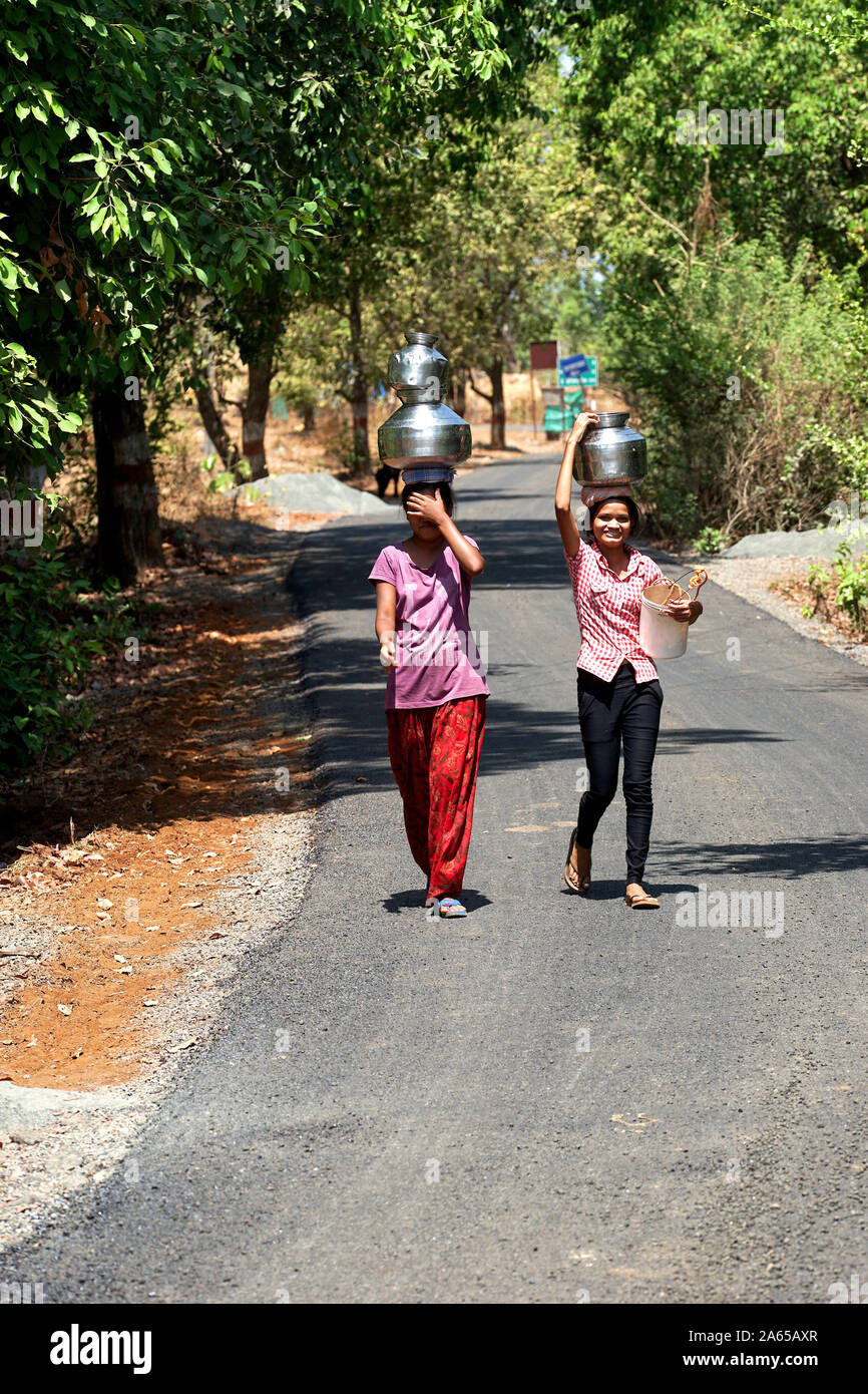 Le giovani ragazze che trasportano pentole di acqua dal bene al mal village, Thane, Maharashtra, India, Asia Foto Stock