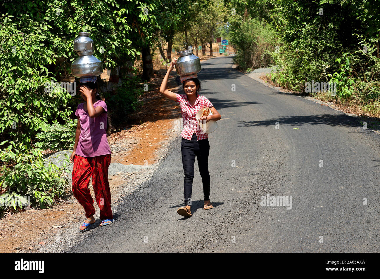 Le giovani ragazze che trasportano pentole di acqua dal bene al mal village, Thane, Maharashtra, India, Asia Foto Stock