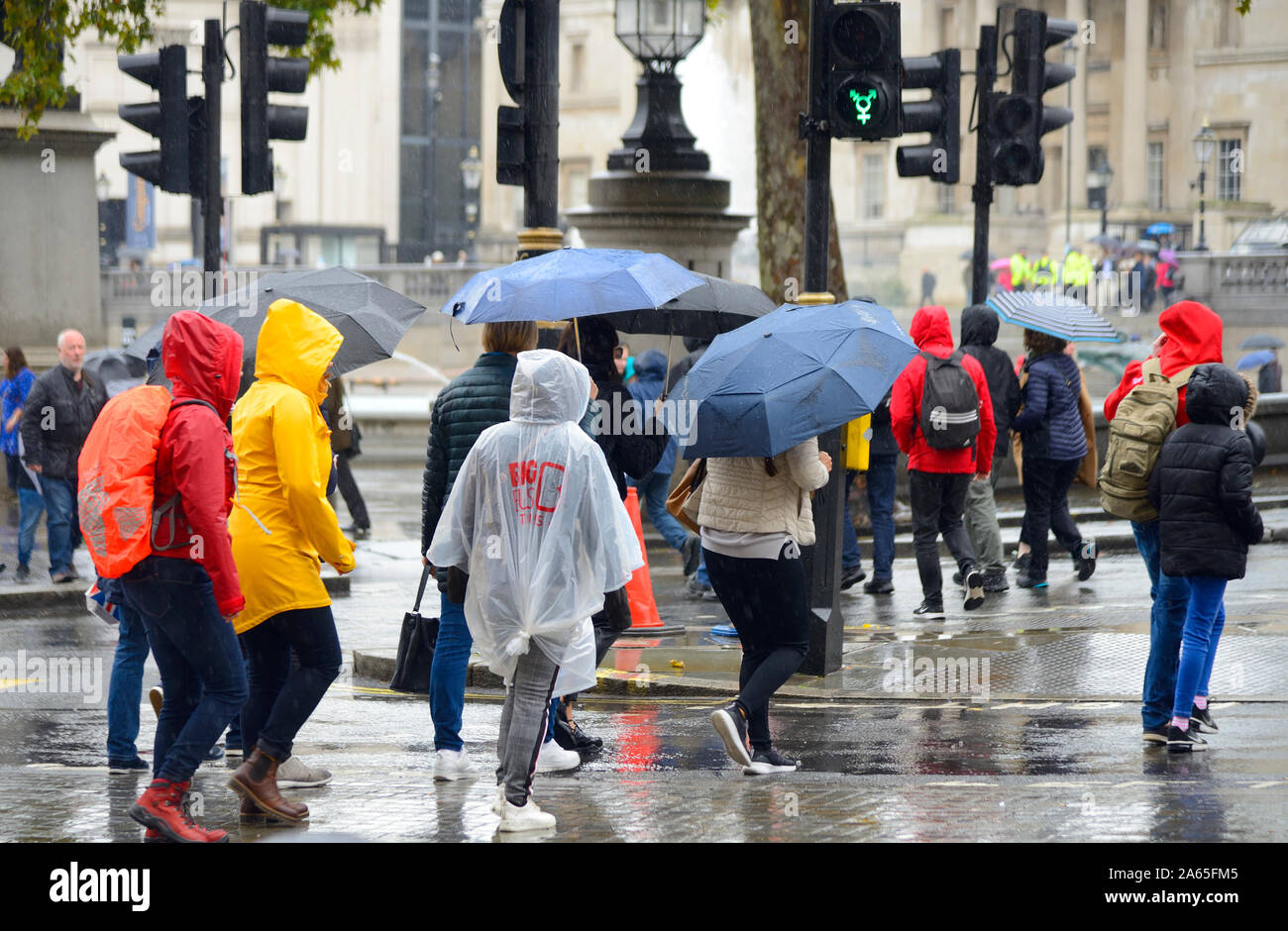 Londra, Inghilterra, Regno Unito. Persone con ombrelloni in Trafalgar Square in un giorno di pioggia Foto Stock