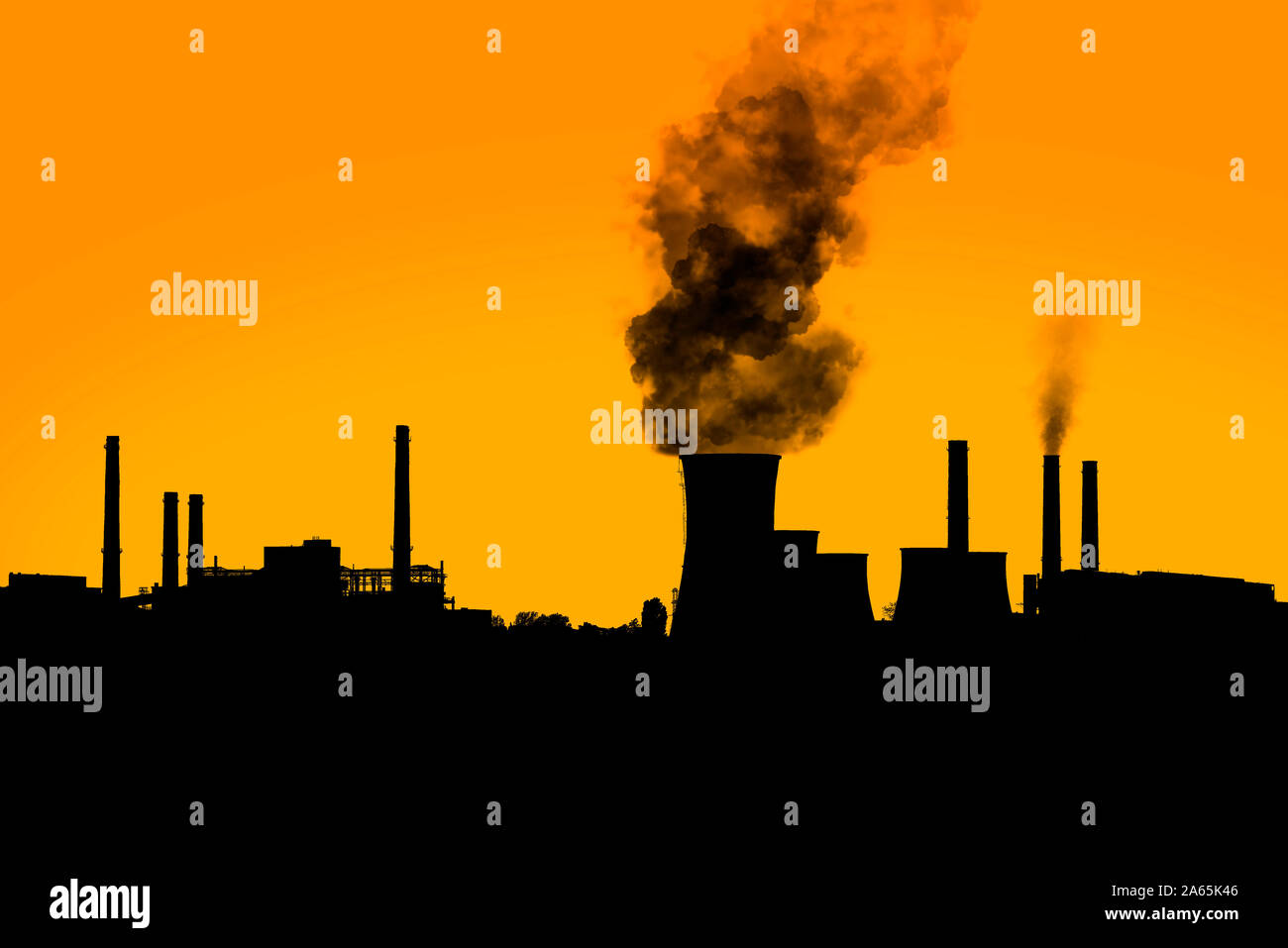 Dark nocivi dal fumo di camini di pianta di potere silhouette sul tramonto arancione chiaro cielo. Foto Stock