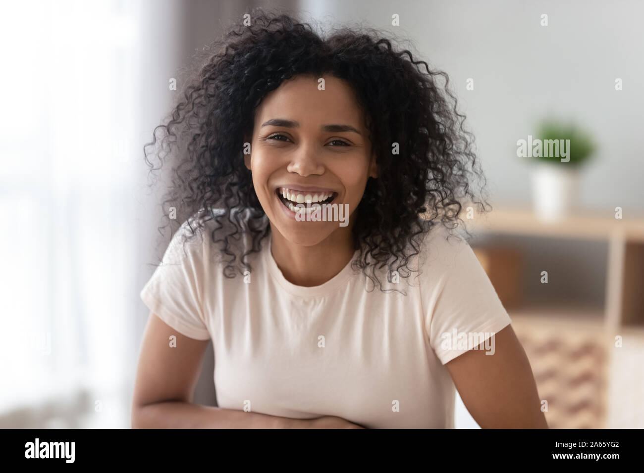 Ritratto di nero sorridente ragazza millenaria che pongono a casa Foto Stock