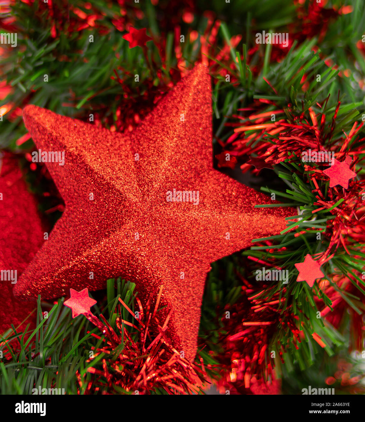 Estrella de Navidad roja con purpurina sobre lecho de hojas verdes Foto Stock