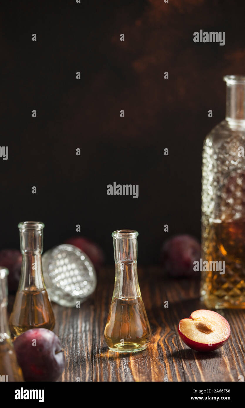 Rakia o rakija tradizionale dei Balcani acquavite di frutta. Acquavite di prugne Slivovica in un vetro che è chiamato cokanj e bottiglia su una tavola di legno Foto Stock