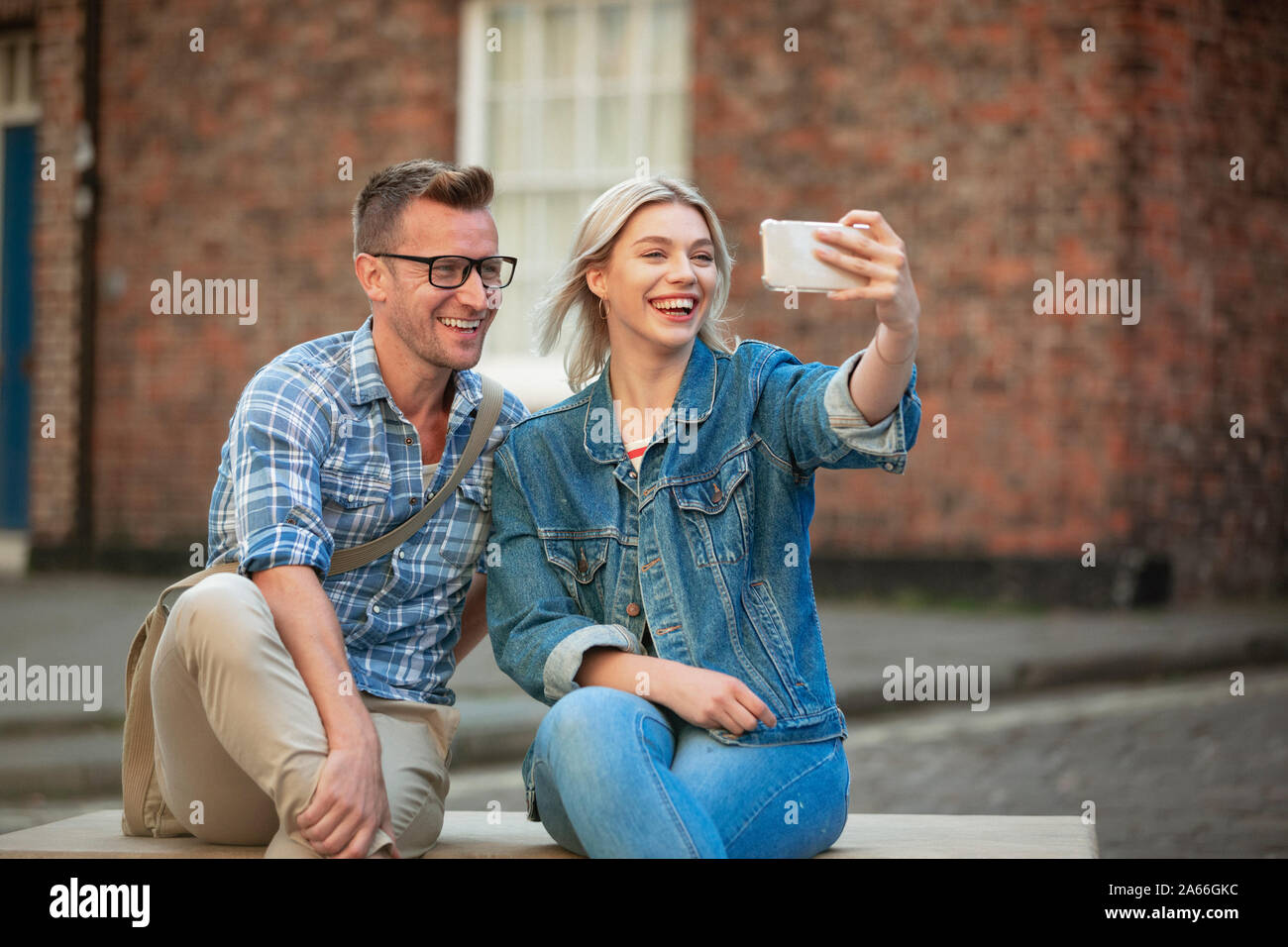 Una donna prendendo un selfie con un uomo mentre seduto su una panchina. Foto Stock