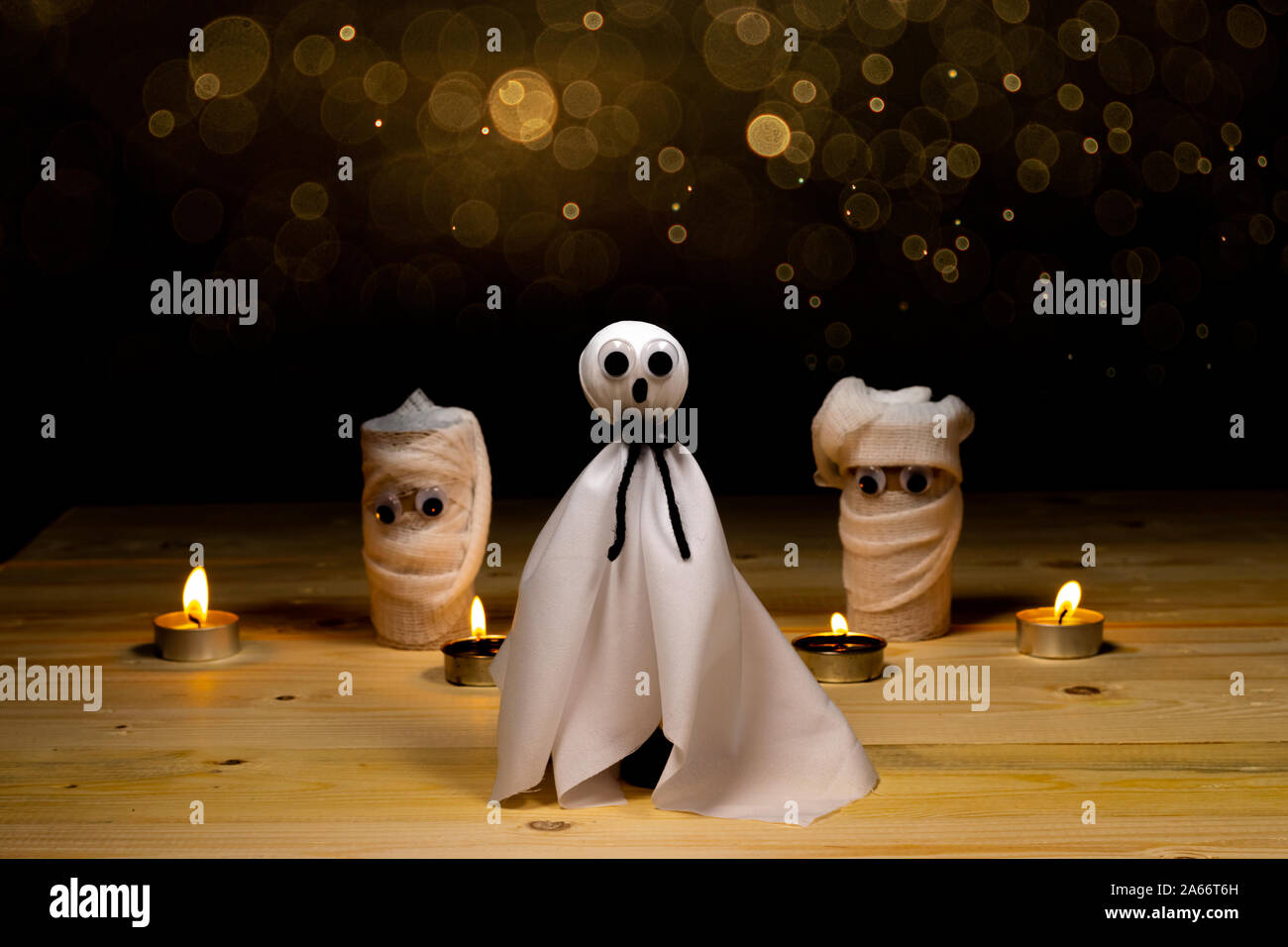 Halloween. Fai da te con golden bokhe. Casper fantasma e le mummie idea creativa dal tubo igienica riciclare e candela su tavola con sfondo nero. Foto Stock