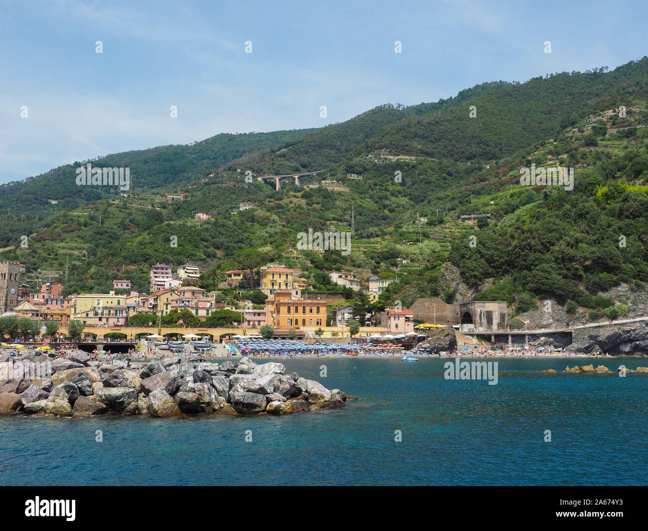 Costa Delle Cinque Terre, Italia. Riva del mare di Monterosso al Mare, Liguria. Vista dal Mar Mediterraneo. Verdi pendii di montagne e case in acqua Foto Stock