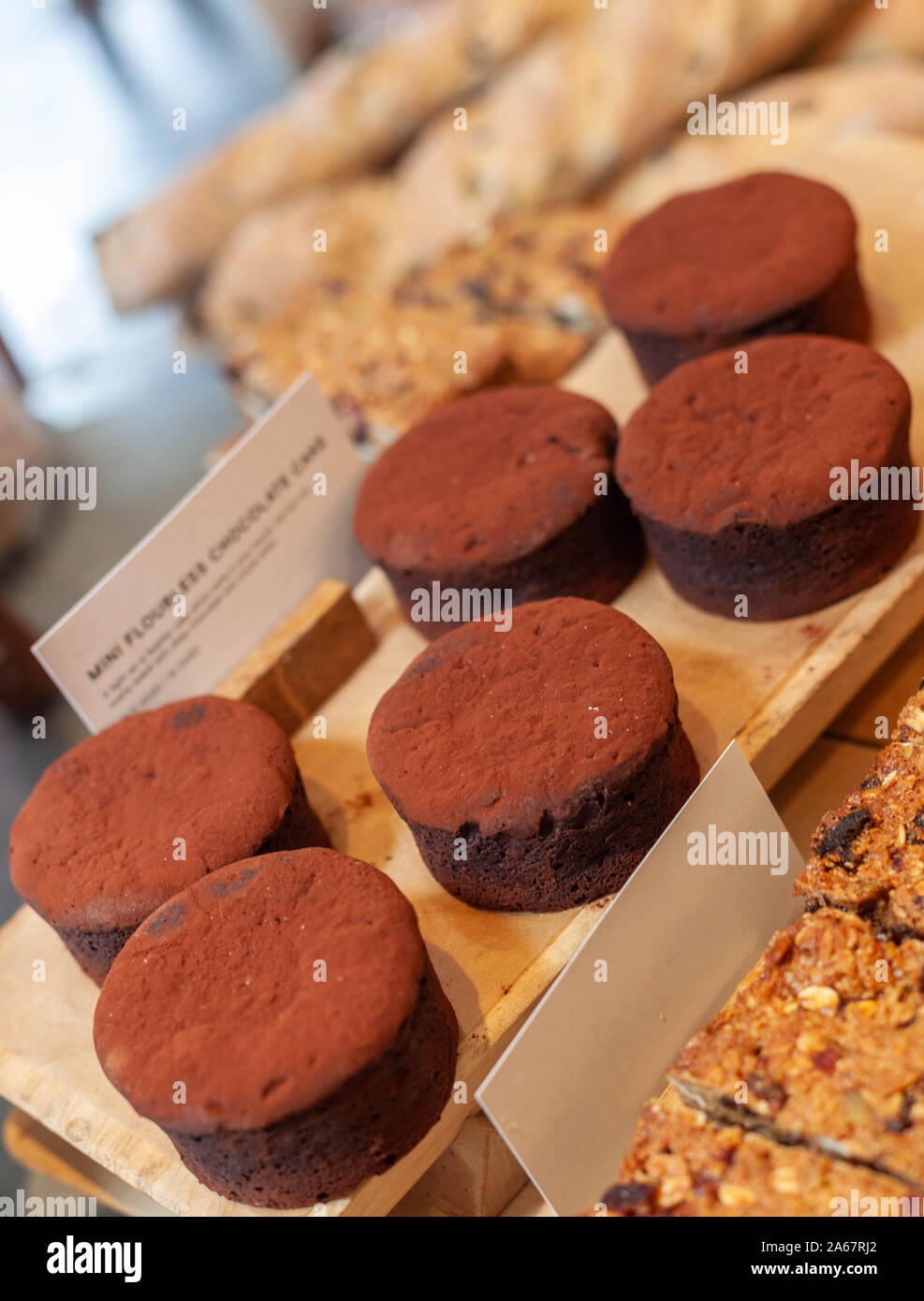 Un vassoio di mini flourless torte al cioccolato sul display all'interno di un panificio. Foto Stock