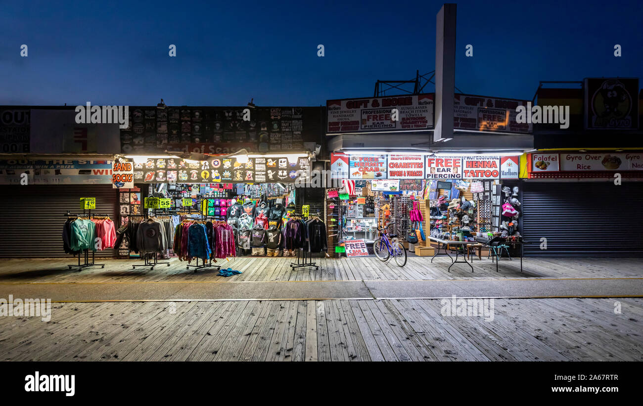 Un piccolo numero di persone a piedi e visitare i negozi e sale da gioco su un quasi vuoto ocean boardwalk di notte quando l'estate è finita. Foto Stock