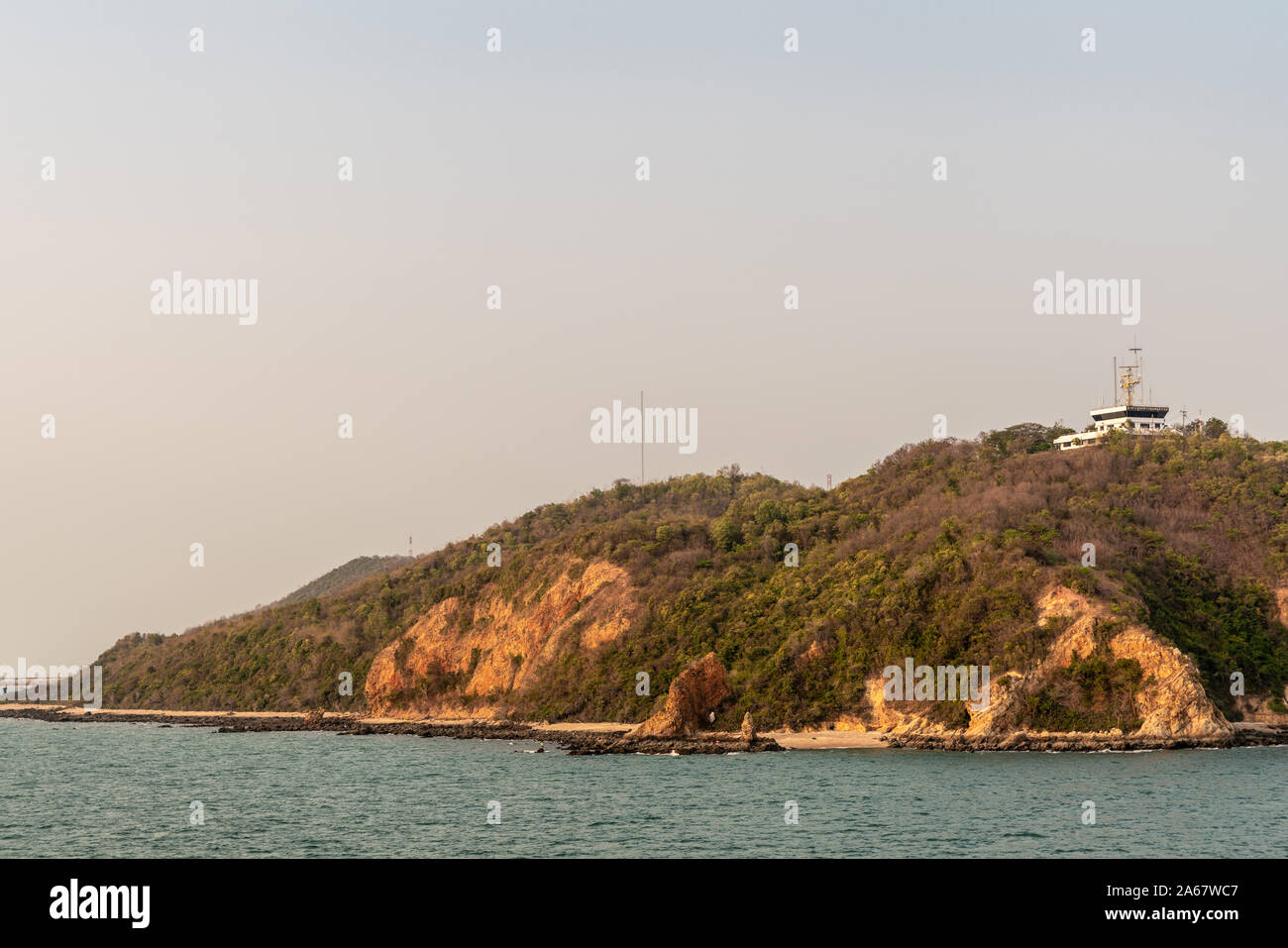 Il Porto di Laem Chabang seaport, Tailandia - 17 Marzo 2019: edificio bianco del controllo portuale e il centro operazioni in marrone-verde collina sopra il porto con antenn Foto Stock