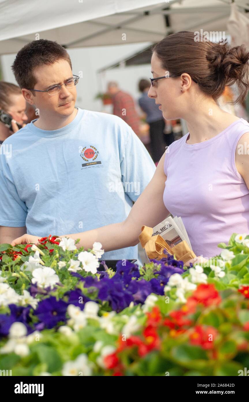 Due persone considerano un acquisto da una stalla di fiori, in una giornata di lancio, in un affollato mercato agricolo all'aperto, Baltimora, Maryland, 12 maggio 2007. Dalla Homewood Photography Collection. () Foto Stock