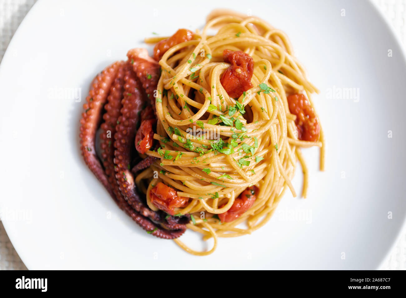 Spaghetti con pomodorini e salsa di polipo, prezzemolo. Gustoso piatto di pasta della cucina italiana. Con vero polipo cotti pronti a mangiare. Foto Stock