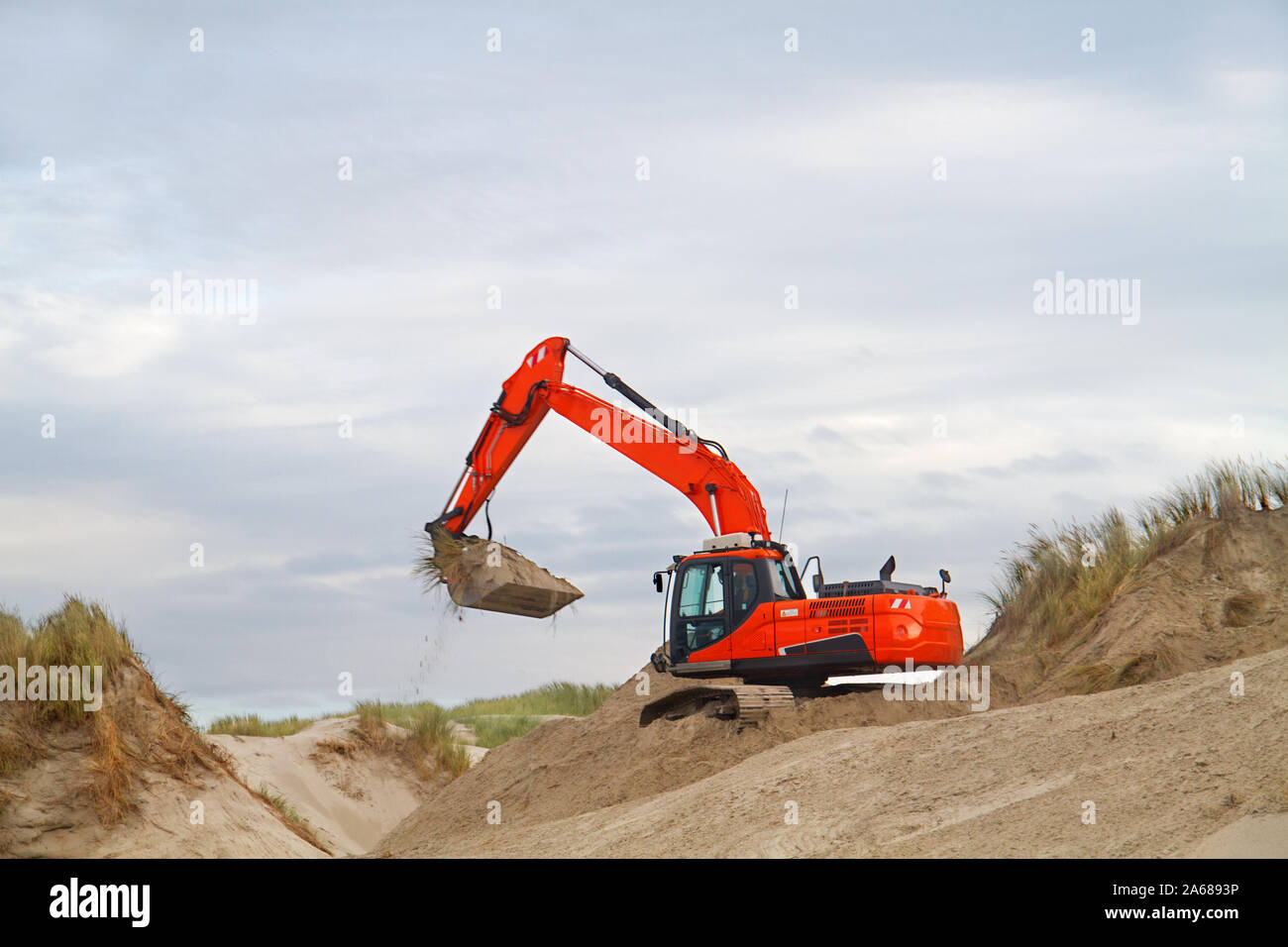 Arancione di lavoro di scavo sul recupero delle dune onda dopo un attacco, il faggio dell'isola olandese di Terschelling Foto Stock Arancione di lavoro di scavo sul recupero delle dune onda dopo un attacco, il faggio dell'isola olandese di Terschelling Foto Stock