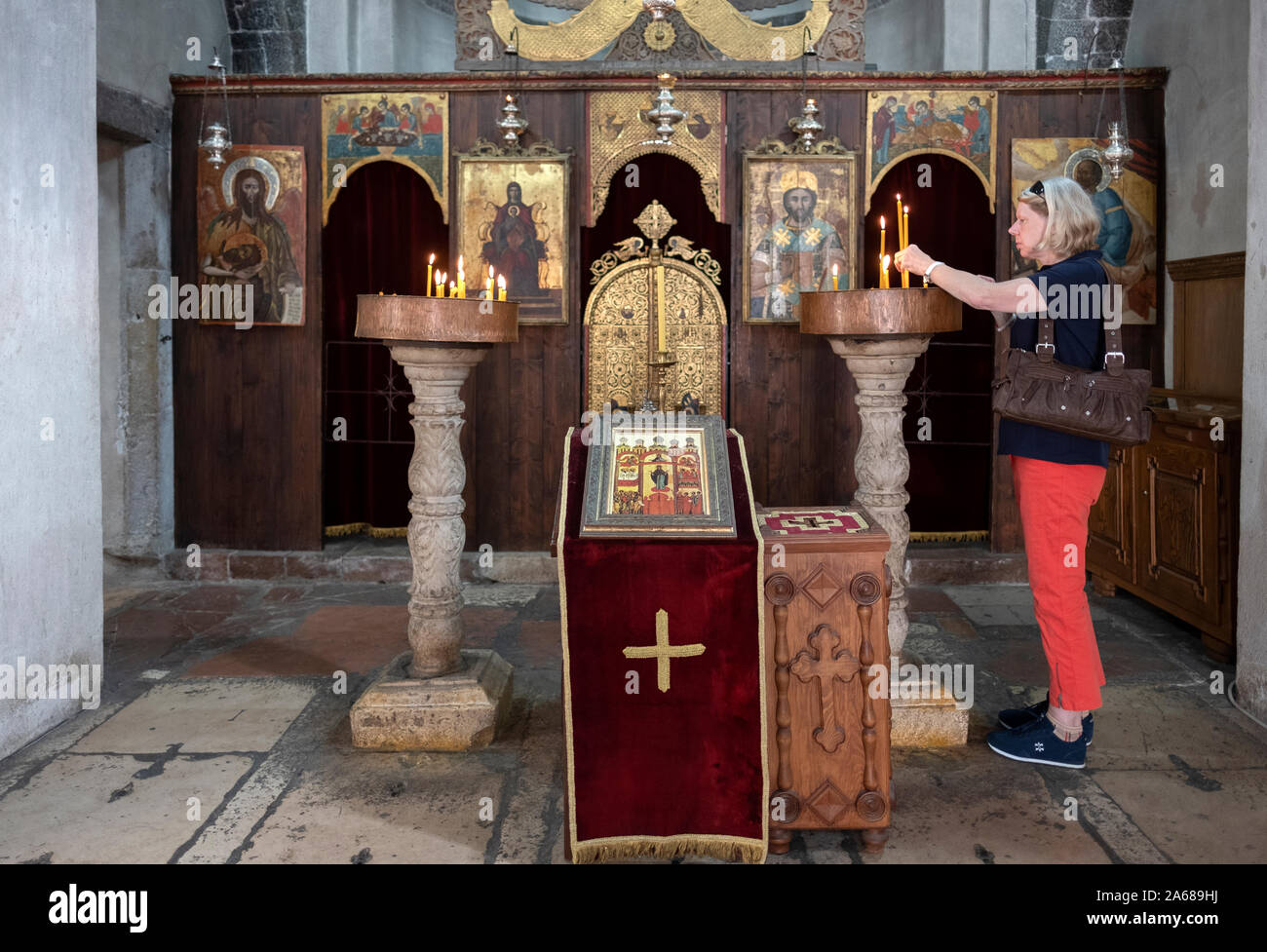 Una touring donna accende una candela in Saint Nicholas Chiesa serbo-ortodossa di Kotor, Montenegro. Foto Stock
