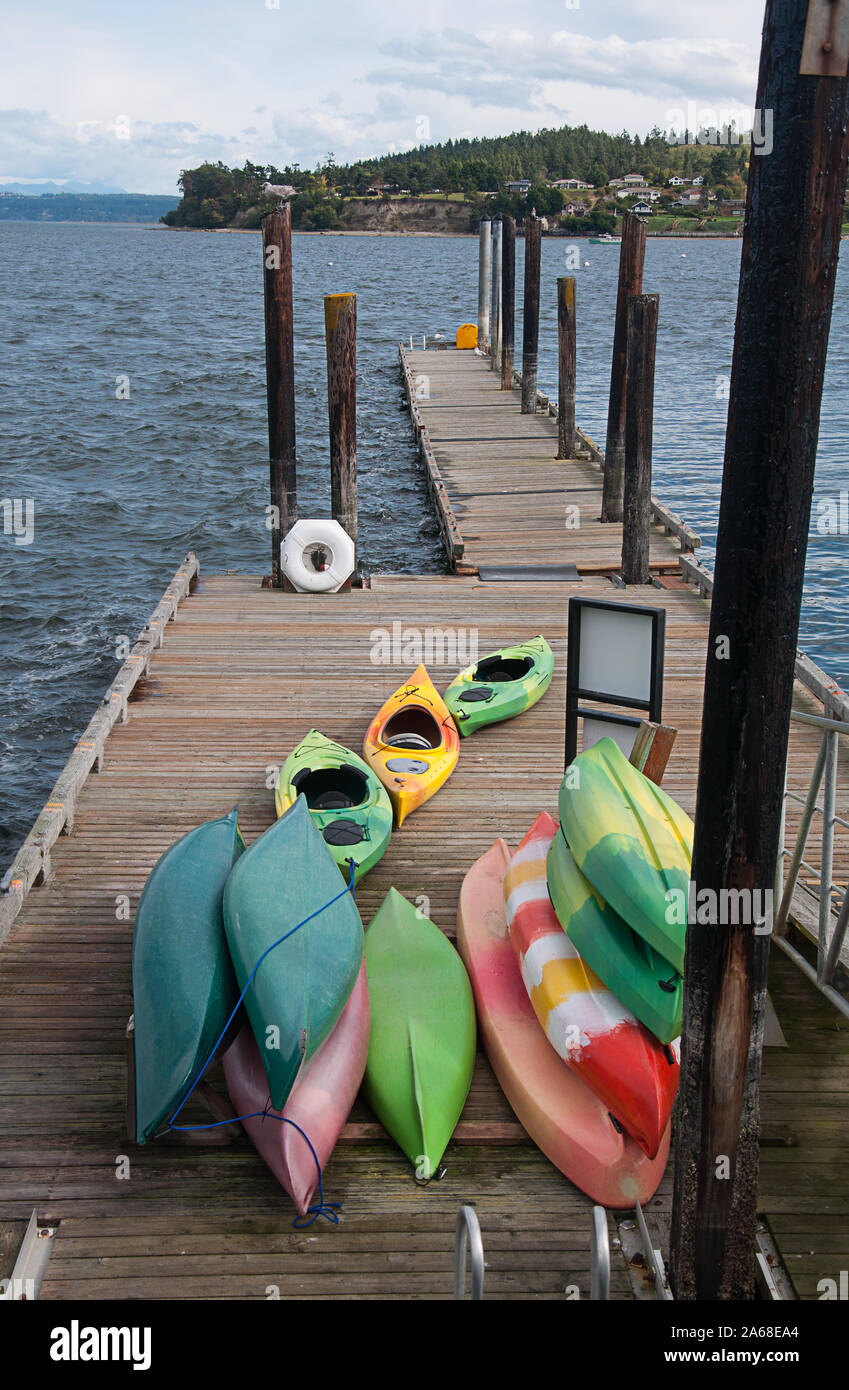 Kayaks colorati sul dock presi in Coupeville Washington nel nord-ovest del pacifico paesaggio. Puget Sound di acqua oceanica con un punto di terra. Foto Stock