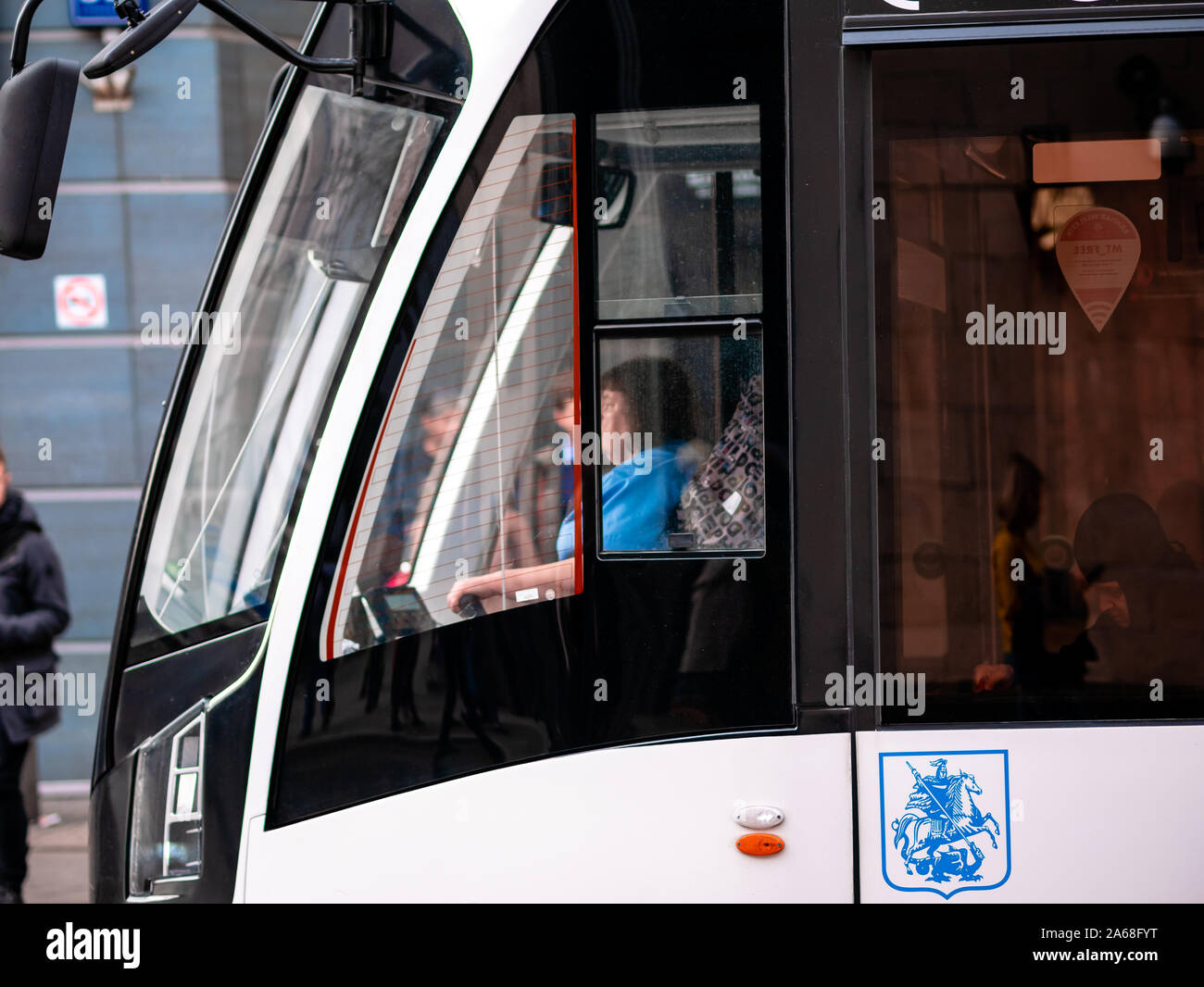 Mosca, Russia - 19 Ottobre 2019: moderno e basso piano tram "Vityaz-M' presso la fermata del bus. Lo stemma di Mosca è blu. Donna auto conducente in cabina Foto Stock