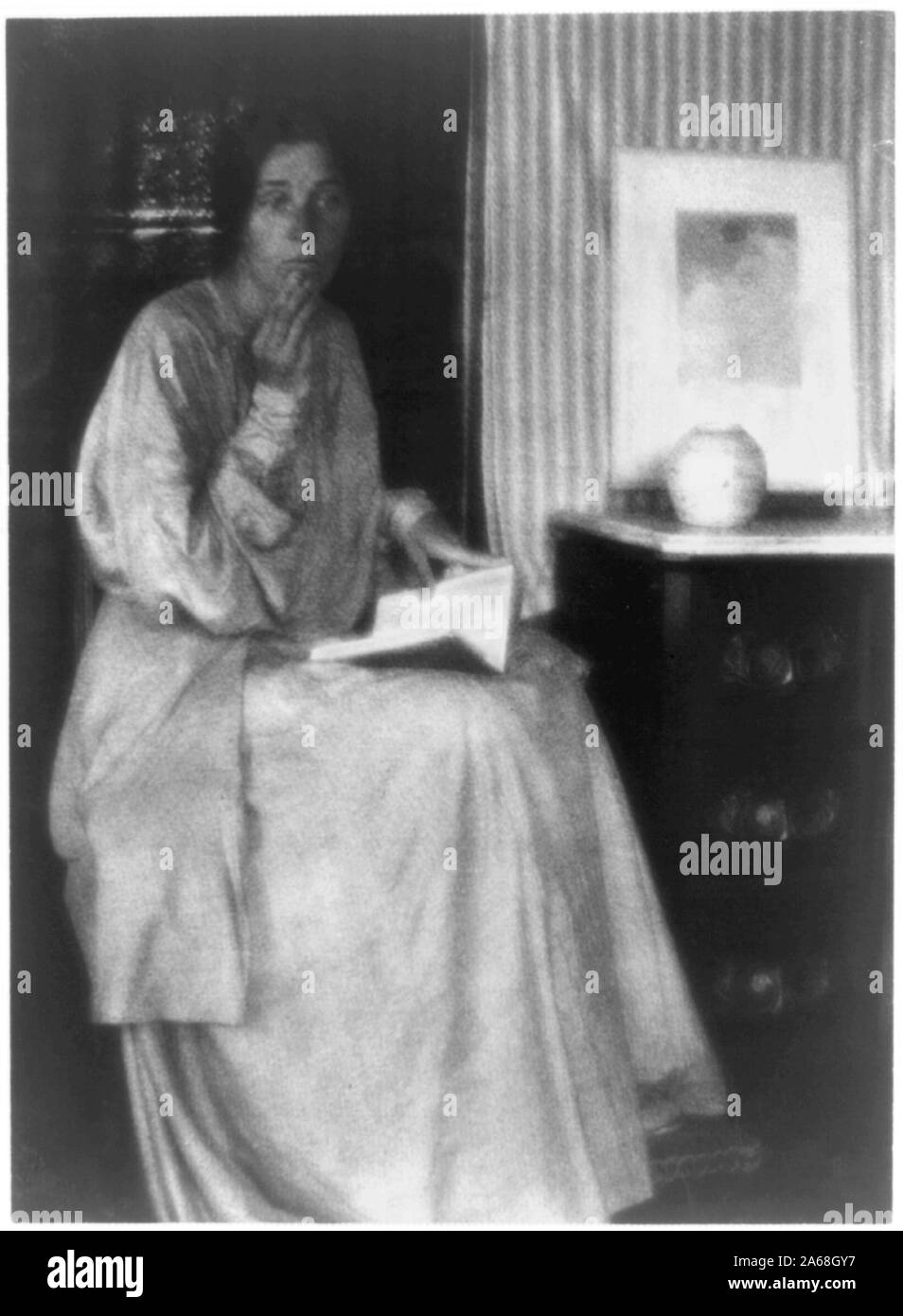 Donna (Beatrice Baxter Ruyl), nel vestire con il libro aperto in giro e le mani alla faccia, seduto Foto Stock