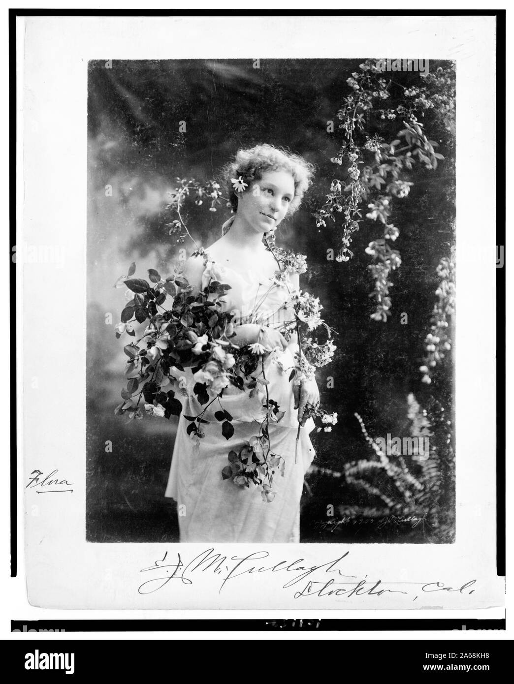 Donna, Flora, ponendo in studio, tre quarti di lunghezza, in piedi, rivolto verso destra, con fiori] / E.J. McCullagh, Stockton, Cal Foto Stock