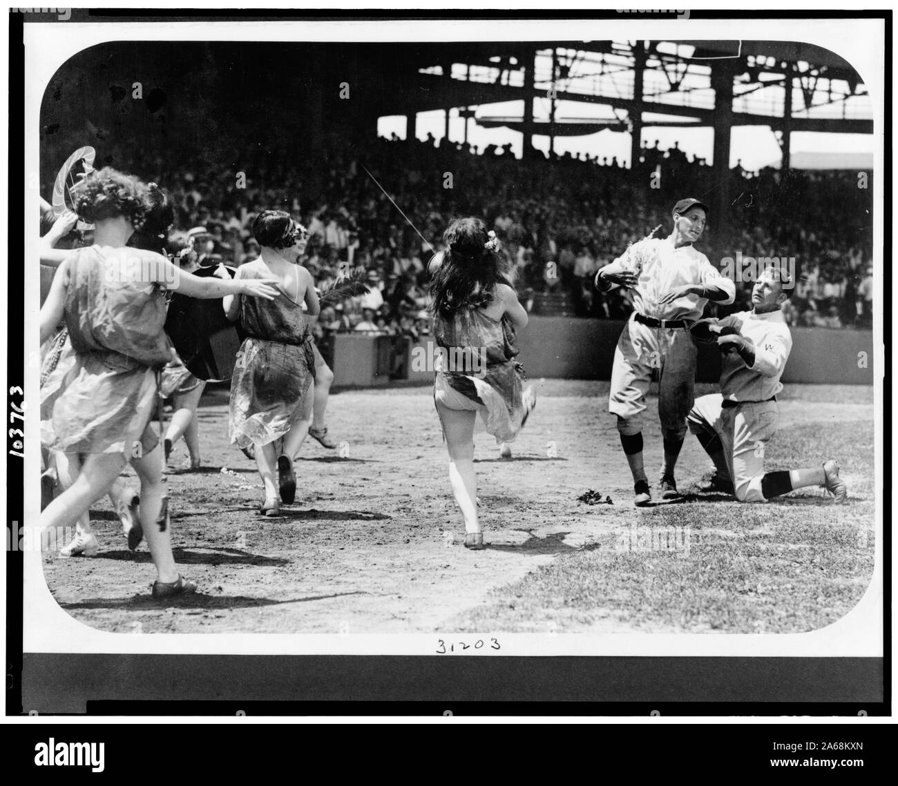 Donne che danzano e due Nazionale di Washington i giocatori di baseball clowning sul campo di baseball Foto Stock