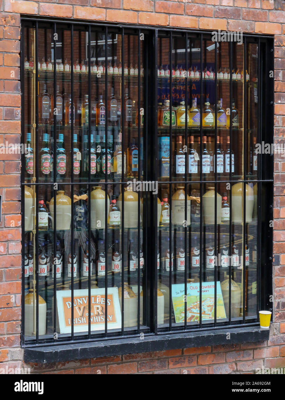 Bottiglie di whisky sul display e per la vendita in un negozio finestra. L'amico a portata di mano è uno specialista di whiskey shop nel quartiere della Cattedrale di Belfast. Foto Stock