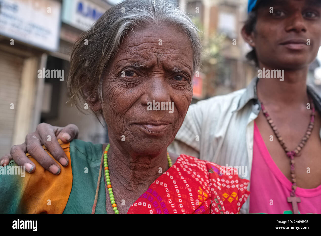 Una baraccopoli abitante in Mumbai, India, posa con il suo braccio intorno a sua madre Foto Stock