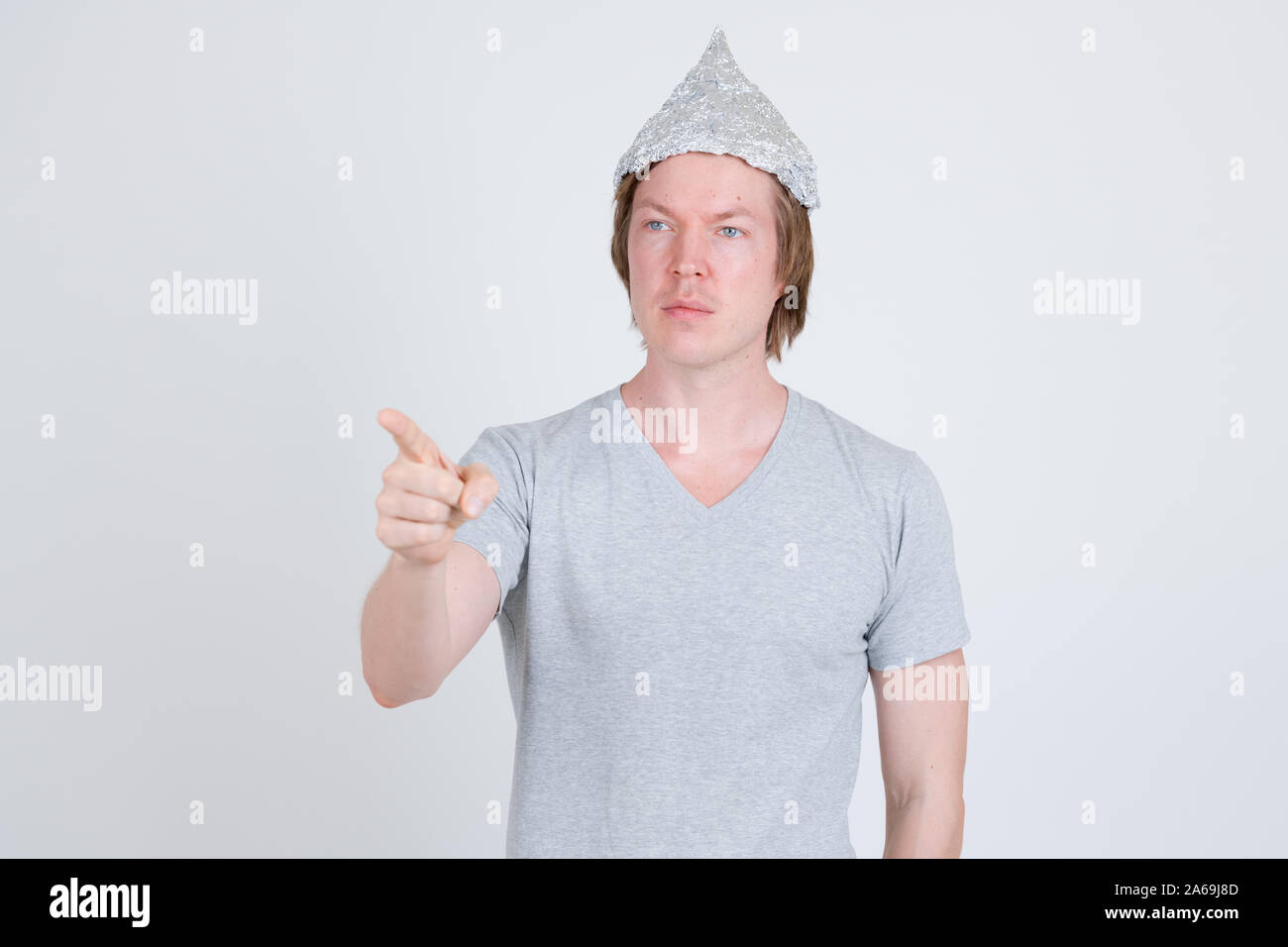 Giovane uomo che indossa la lamina di tin hat come teoria della cospirazione concetto puntare il dito Foto Stock
