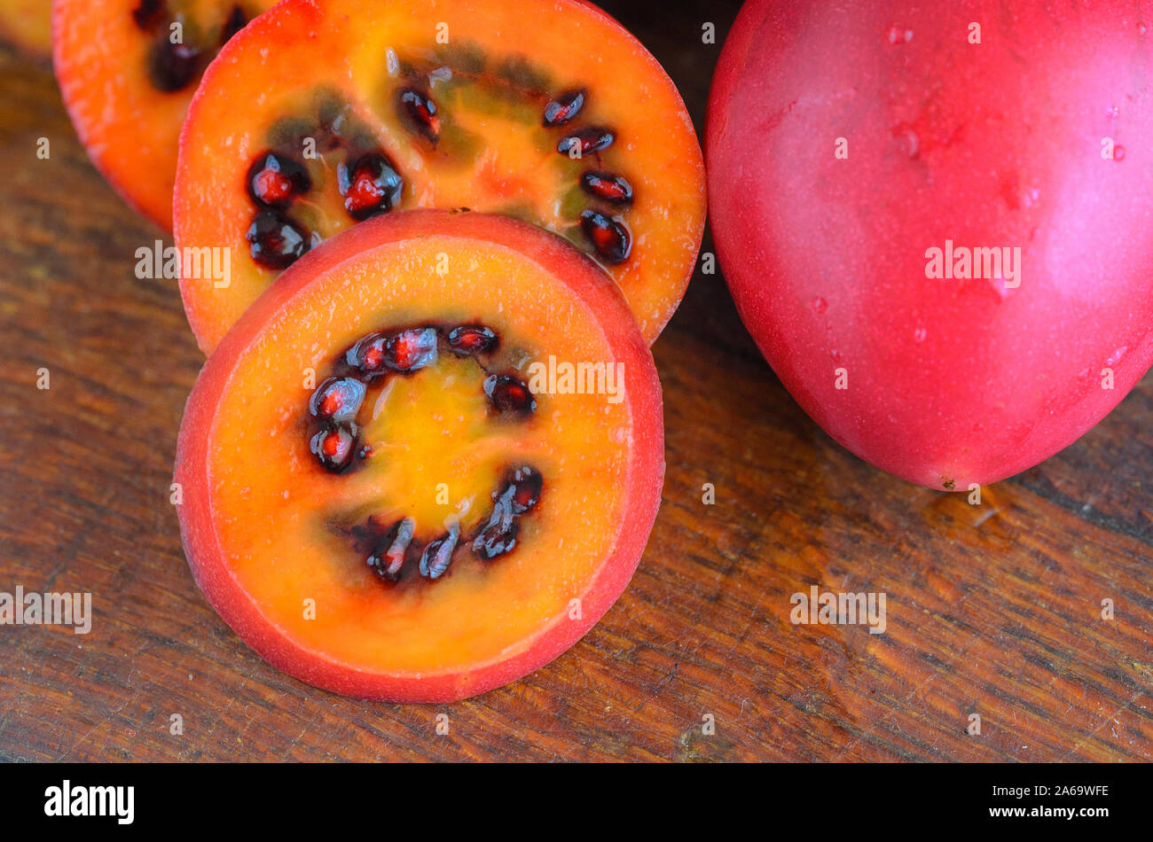 Red tamarillo o albero pomodoro tagliato a fette tagliate sul bordo. La frutta esotica Tamarillo sfondo. Foto Stock