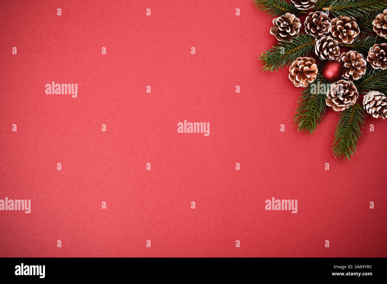 Natale e Anno Nuovo composizione. Stagionale della scheda Messaggi di saluto concetto con pigne nelle quali, evergreen rami su sfondo rosso. Natale, inverno, anno nuovo. Foto Stock