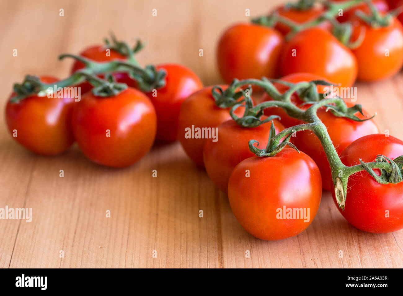 Pomodori ciliegia su un ramo isolato su sfondo di legno - Vista laterale foto con messa a fuoco selettiva Foto Stock