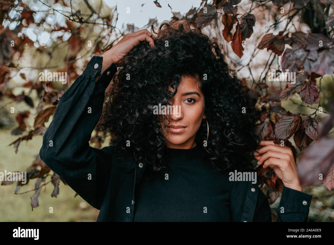 Affascinante Ritratto di giovane donna africana con capelli ricci, Street Style, ponendo all'aperto Foto Stock