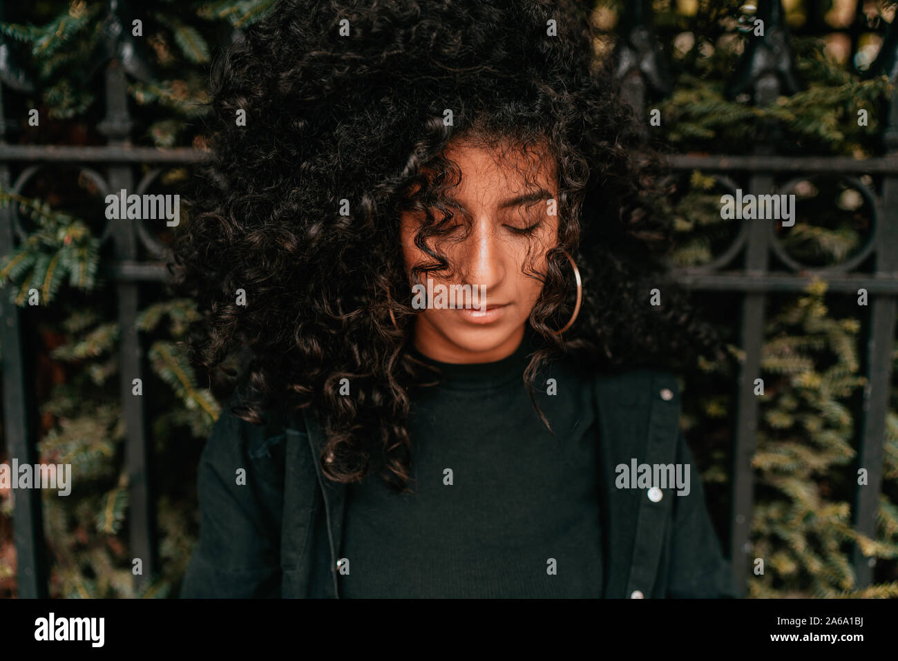 Affascinante Ritratto di giovane donna africana con capelli ricci, Street Style, ponendo all'aperto Foto Stock