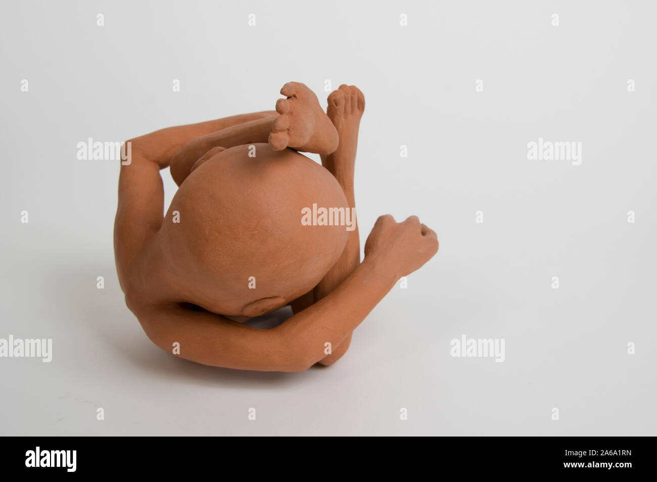La figura in argilla di un neonato si arricciata in posizione fetale Foto Stock