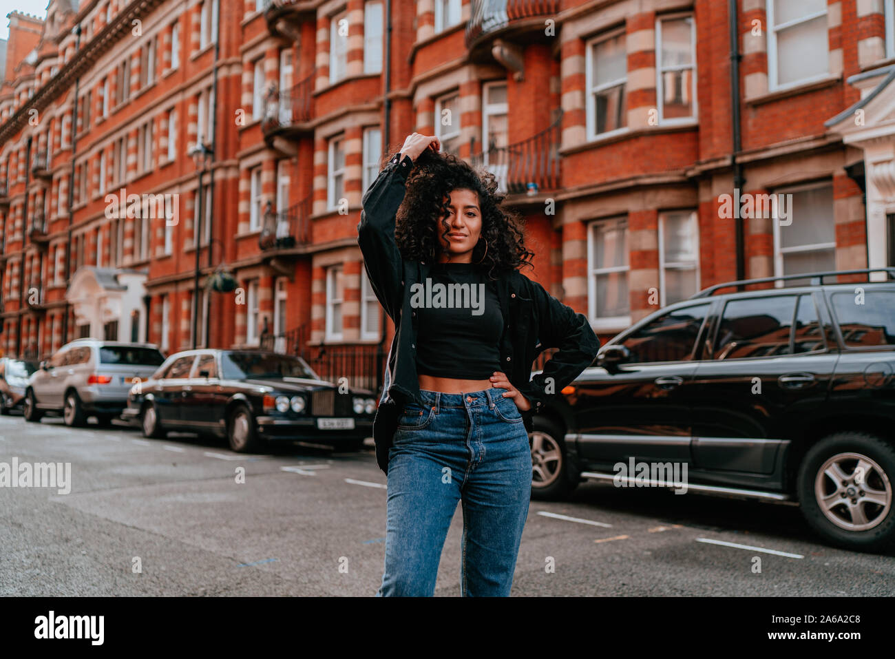 Affascinante Ritratto di giovane donna africana con capelli ricci, Street Style, ponendo all'aperto Foto Stock