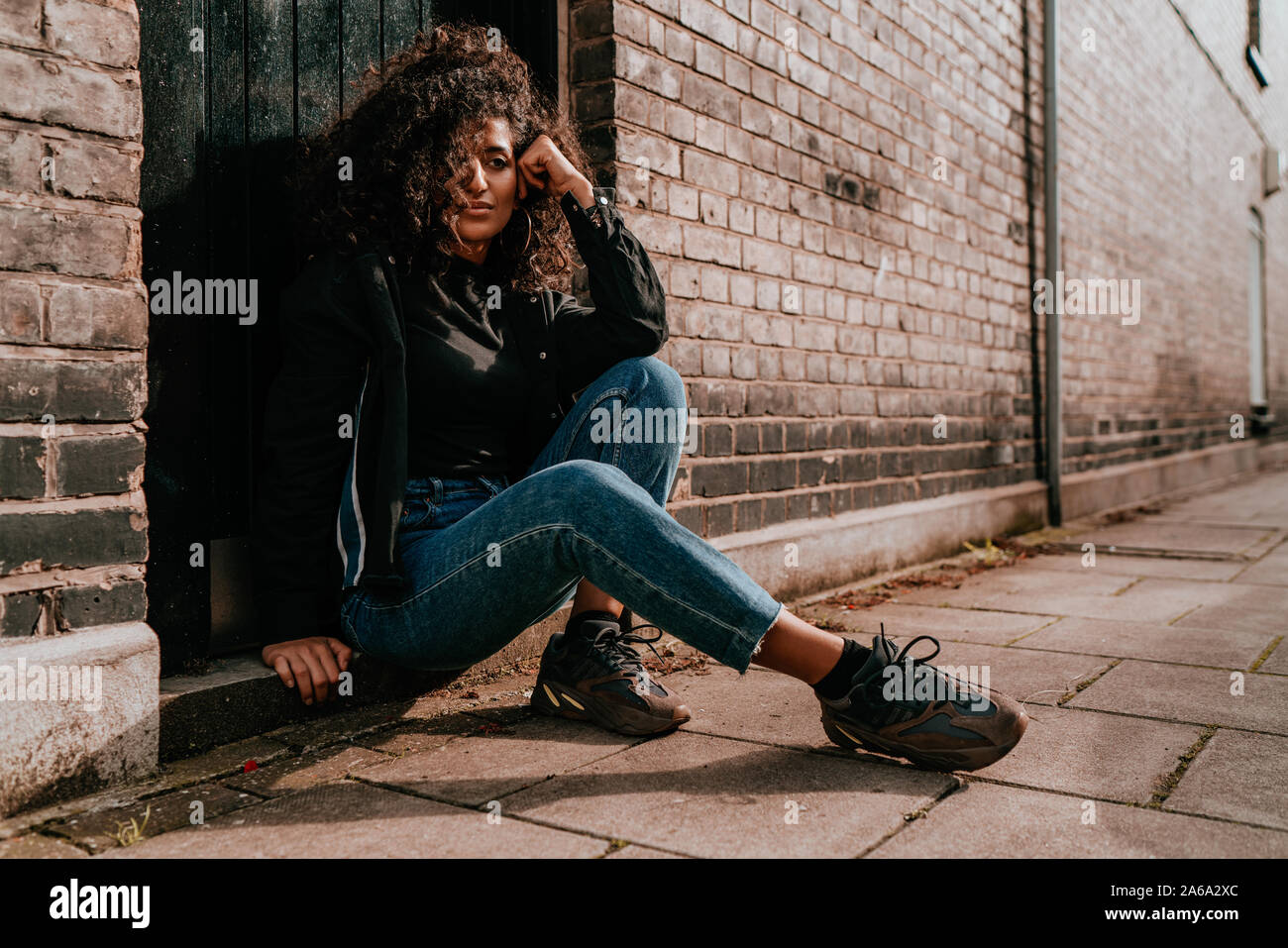 Affascinante Ritratto di giovane donna africana con capelli ricci, Street Style, ponendo all'aperto Foto Stock