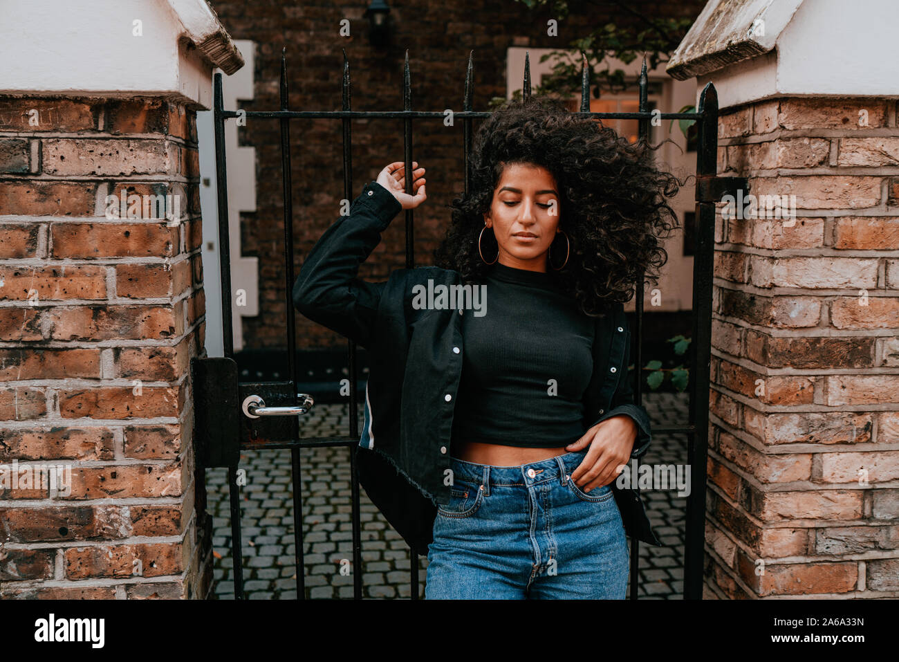 Affascinante Ritratto di giovane donna africana con capelli ricci, Street Style, ponendo all'aperto Foto Stock