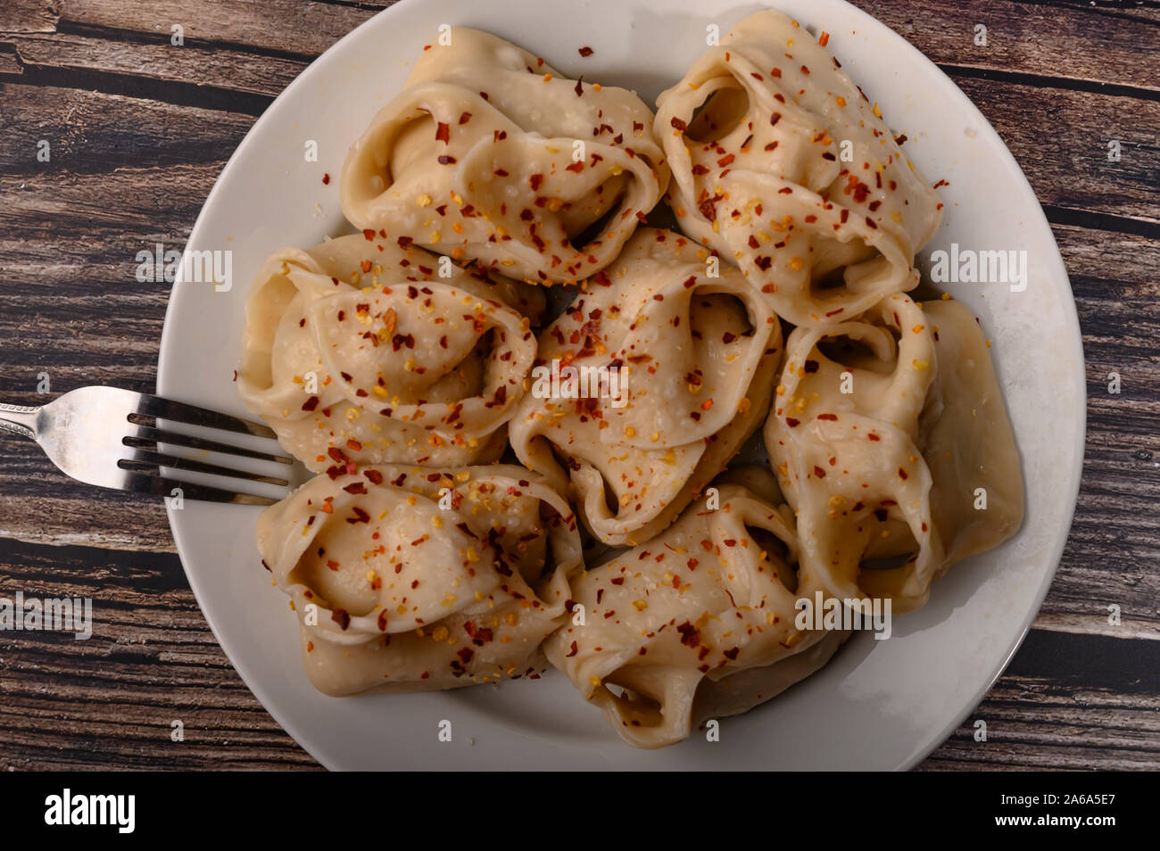 Bollito di manti con la carne su un piatto con spezie su di un tavolo di legno. Close up Foto Stock