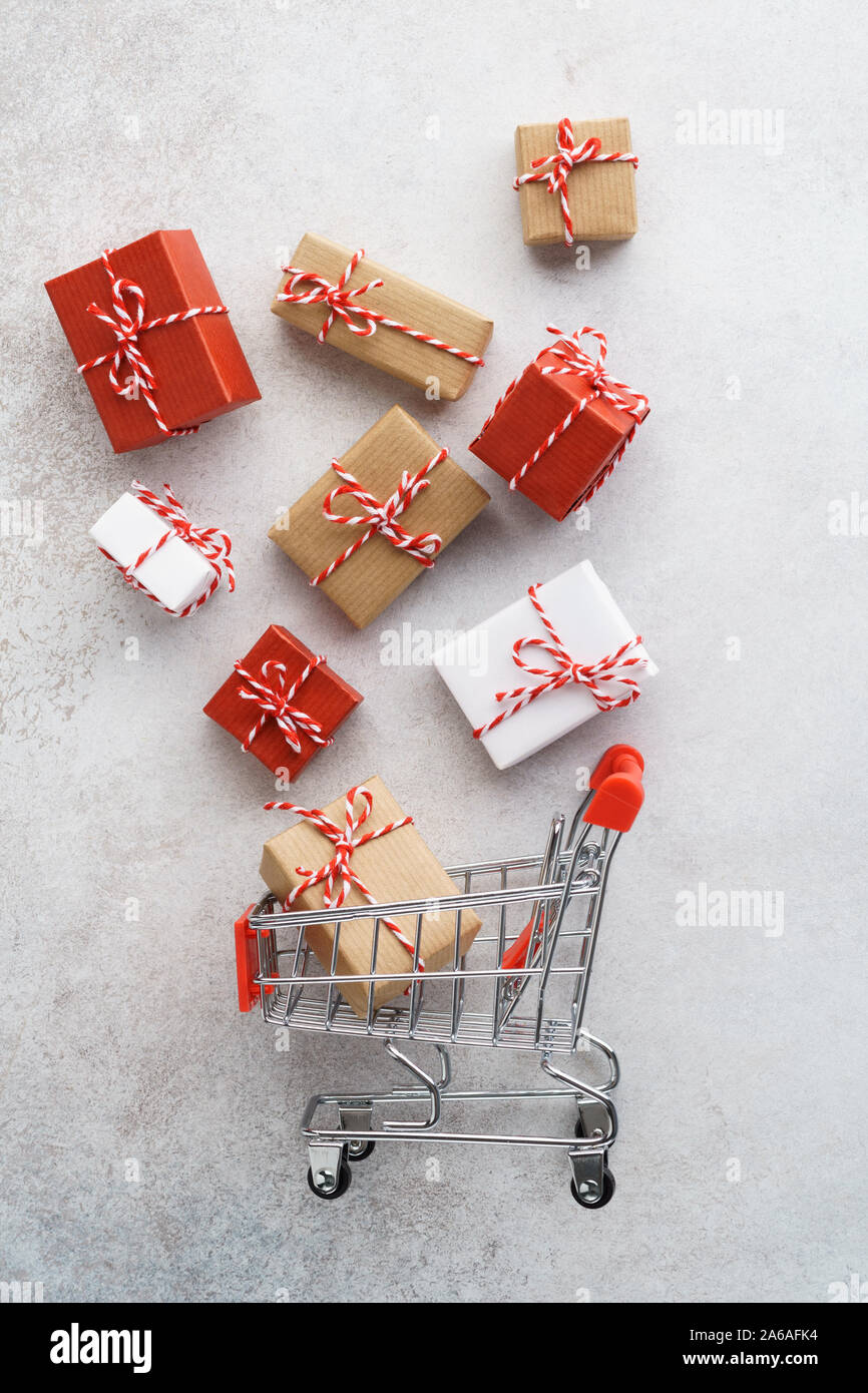 Confezioni regalo volare al di fuori di un carrello su sfondo grigio chiaro. Vendita stagionali e convenienti. Preparazione di natale. Foto Stock